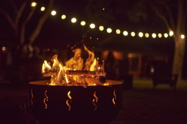 Bonfire burning in a garden a summer night, unknown people in the background.dark