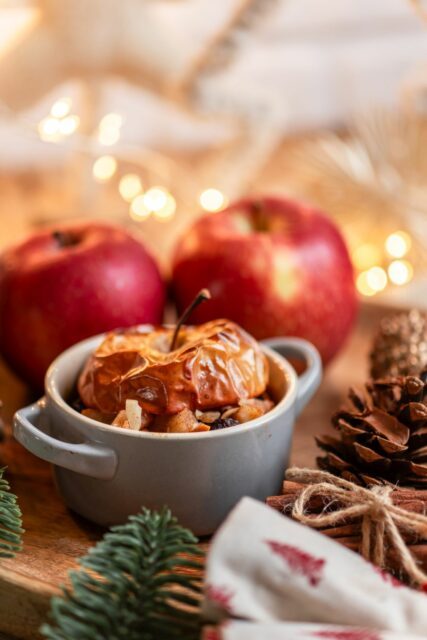 Baked Apple dessert with Nuts and cinnamon on cozy Christmas table at Christmas market